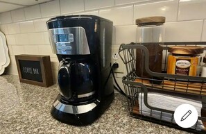 A coffee maker on a kitchen counter next to a sign that reads "Coffee Bar."