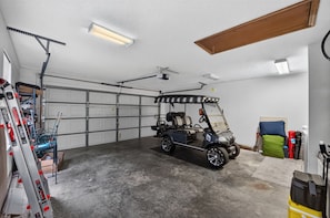Eine Garage mit Golfwagen, Deckenventilator und Betonboden.