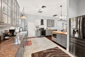 A modern kitchen with stainless steel appliances, grey cabinetry, and a central island.