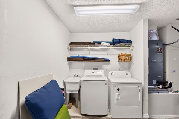 Un cuarto de lavandería con ropa apilada, una lavadora y una secadora.