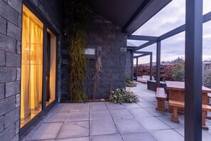 A covered outdoor area with a stone wall, a wooden bench, and a potted plant. - Black Stilt Retreat, STUNNING luxury property (Twizel)