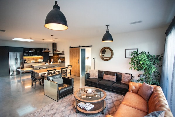 A modern living room with a sofa, coffee table, and dining area. - Black Stilt Retreat, STUNNING luxury property (Twizel)