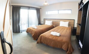 Habitación de hotel con dos camas, un ventanal grande, un armario y una lámpara en el techo.