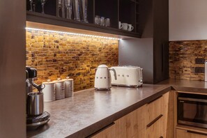 A kitchen with a brick backsplash, a coffee machine, a toaster, and a kettle. - Black Stilt Retreat, STUNNING luxury property (Twizel)