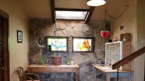 A rustic kitchen with a stone wall, wooden furniture, and a small window with stained glass. - Honey's Suite at The Sage Guesthouse formerly the 19th Hole (Alpine)