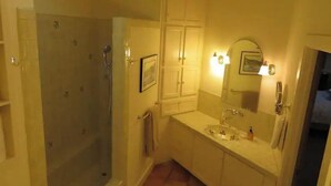 A bathroom with a glass-enclosed shower, a sink with a mirror, and a towel rack. - Honey's Suite at The Sage Guesthouse formerly the 19th Hole (Alpine)