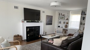 A modern living room with a fireplace, a sofa, a coffee table, and a television. - Modern Colonial House  (Yonkers)