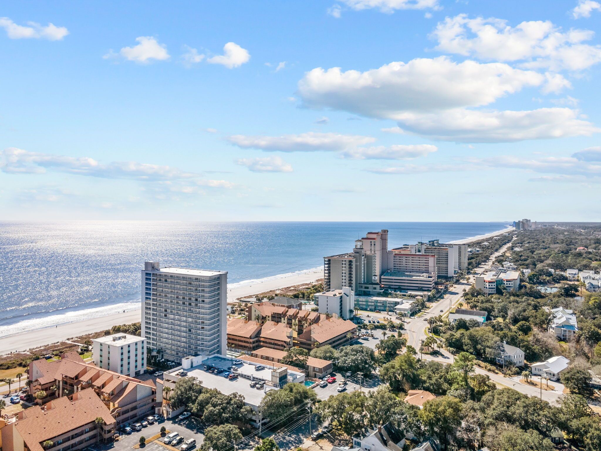 Paisagem costeira urbana com edifícios altos, uma praia e uma combinação de construções residenciais e comerciais.