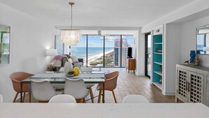 Ett modernt matområde med utsikt över stranden, en kristallkrona och ett stort fönster.