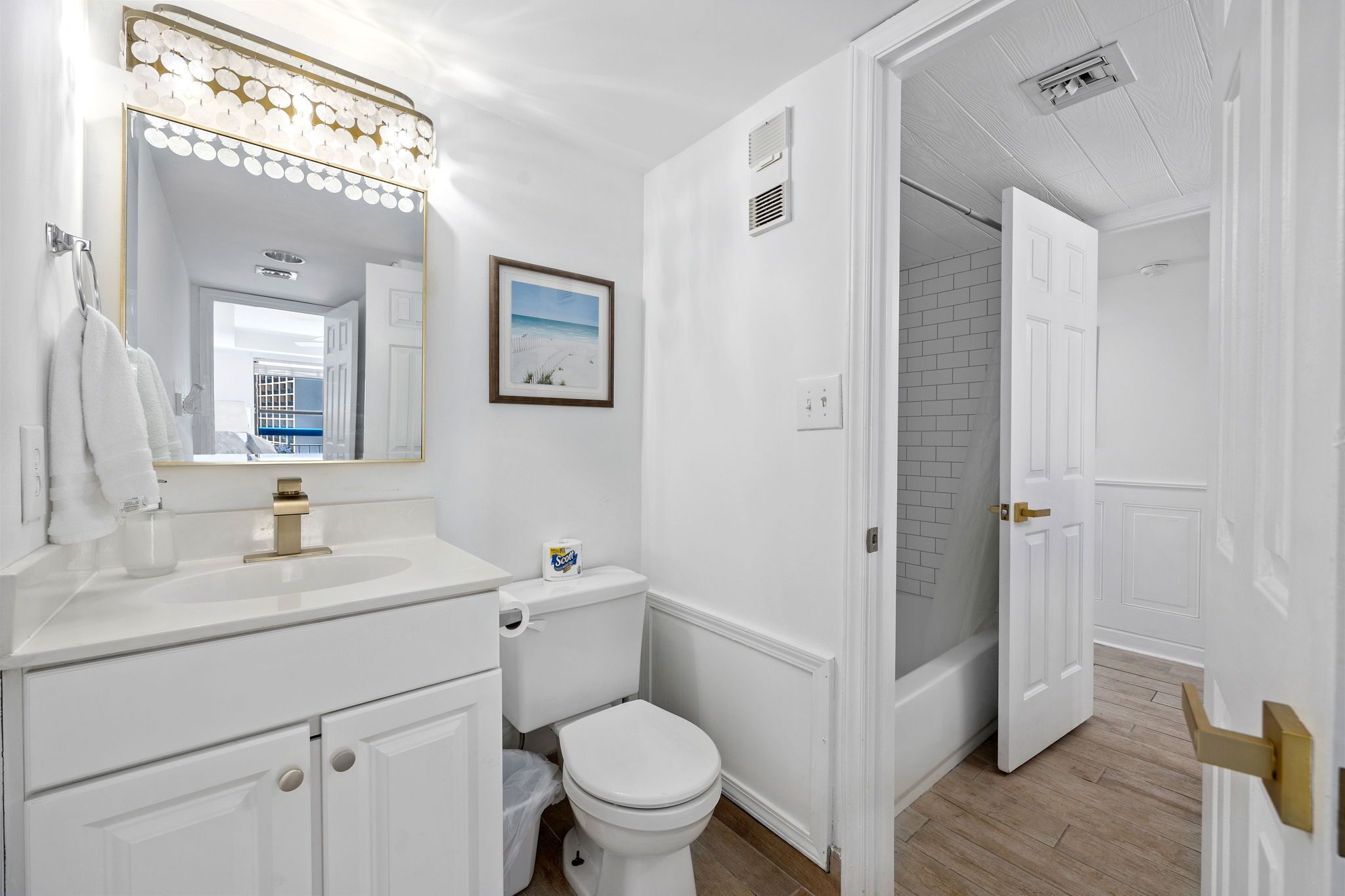 A modern bathroom with a white sink, toilet, and shower area.