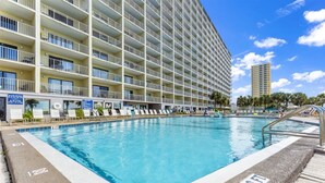 Ein Hotel mit großem Pool, mehreren Balkonen und blauem Himmel.