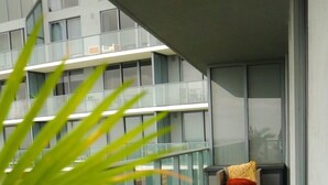Un balcón con una silla, una mesa pequeña, una planta y equipo de ejercicios.