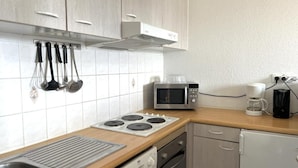 Moderni keittiö, jossa on ruostumattomasta teräksestä valmistettu liesi, mikroaaltouuni, kahvinkeitin ja astianpesukone.