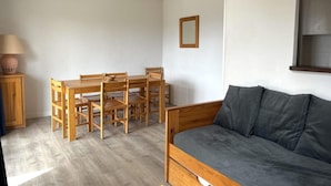 Huoneessa on puinen ruokapöytä ja -tuolit, harmaa sohva ja lamppu.