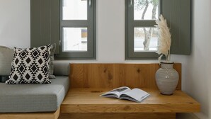 Un coin salon accueillant avec un banc en bois, un canapé gris et un coussin à motifs.