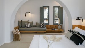 Une chambre confortable avec un banc intégré, un lit doté d’une tête de lit blanche et deux fenêtres équipées de volets.