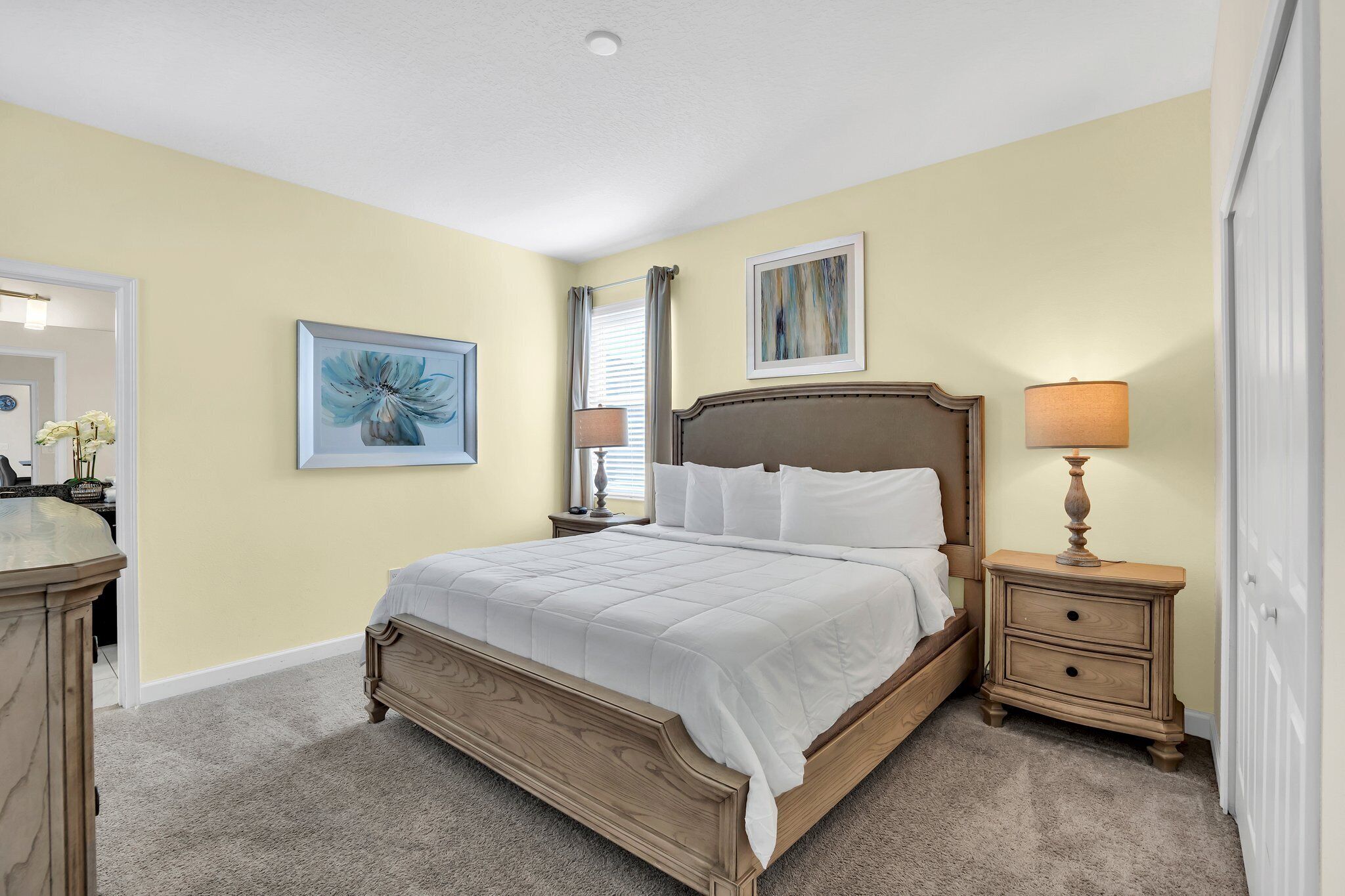 A bedroom with a wooden bed, a nightstand with a lamp, and two framed pictures on the wall.
