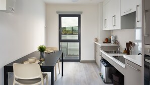 Una cucina moderna con mobili bianchi, un piano di lavoro nero e un'area pranzo con tavolo e sedie.