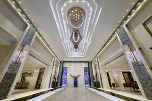 Eine großzügige Lobby mit einem zentralen Kronleuchter, Marmorböden und modernem Design.