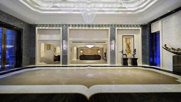 A spacious lobby with a central reception desk, a chandelier, and a view of the interior.