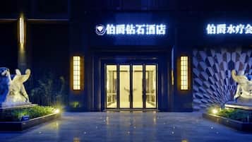 A hotel entrance with a reflective floor, two illuminated statues, and a large fan-shaped wall design.