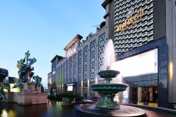 A hotel facade with a large digital display, a fountain, and a statue in the foreground. - Count Diamond Hotel (Longli)