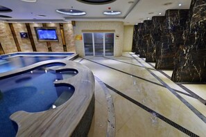 Zona de piscina con diseño curvo, una pantalla de televisión y una puerta que da a otra habitación.