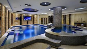 A large indoor swimming pool with a hot tub, a television screen, and a stone pillar. - Count Diamond Hotel (Longli)