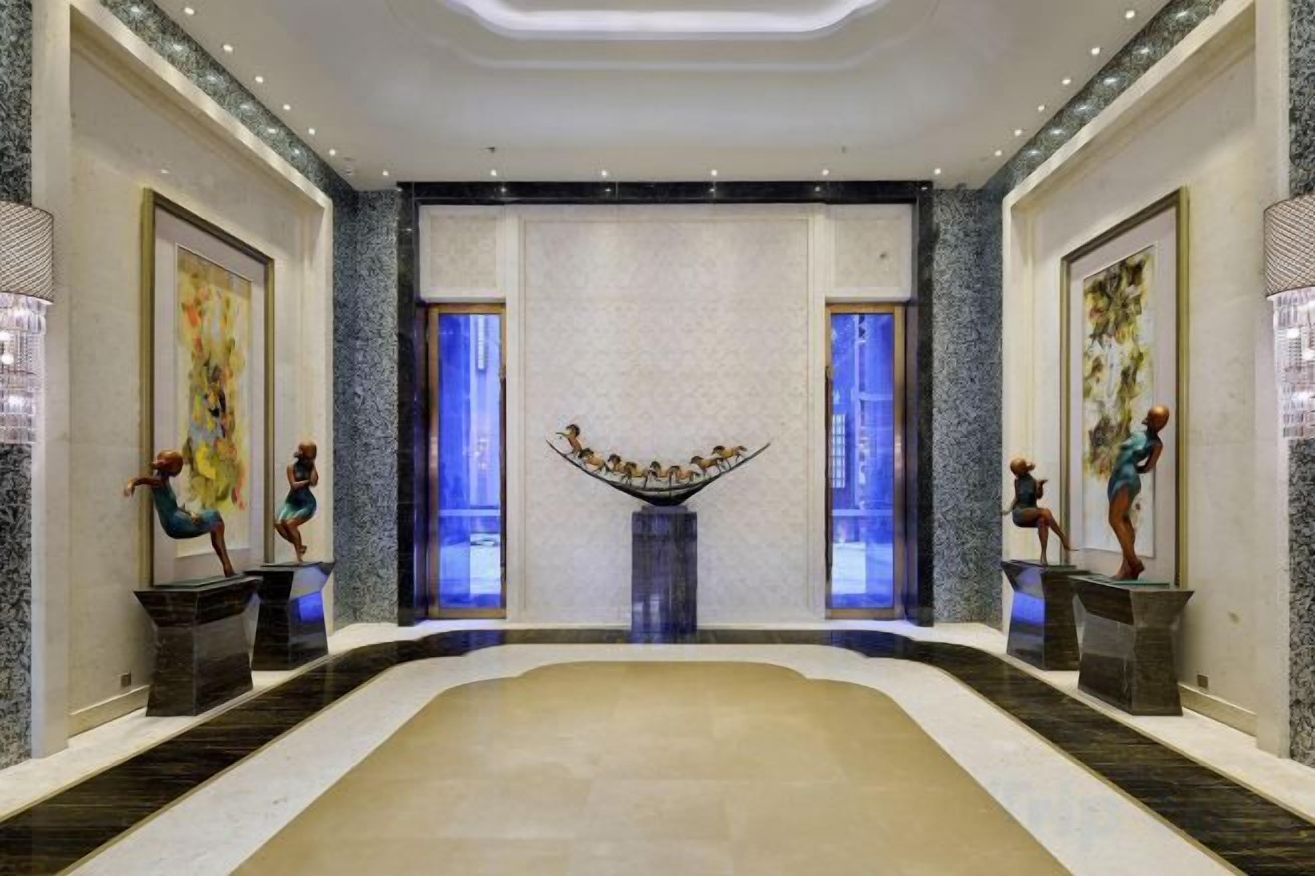 A spacious lobby with a central fountain, marble flooring, and framed artwork on the walls.