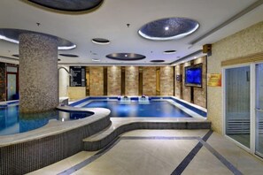 Un espace piscine comprenant un jacuzzi, un revêtement de sol en carrelage et un pilier en pierre.