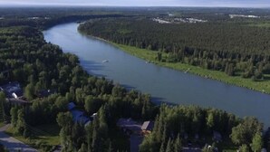 A river winding through a densely forested area with a small settlement on one side.