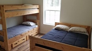 A room with two wooden bunk beds, one with a lower bunk and the other with a full bed.