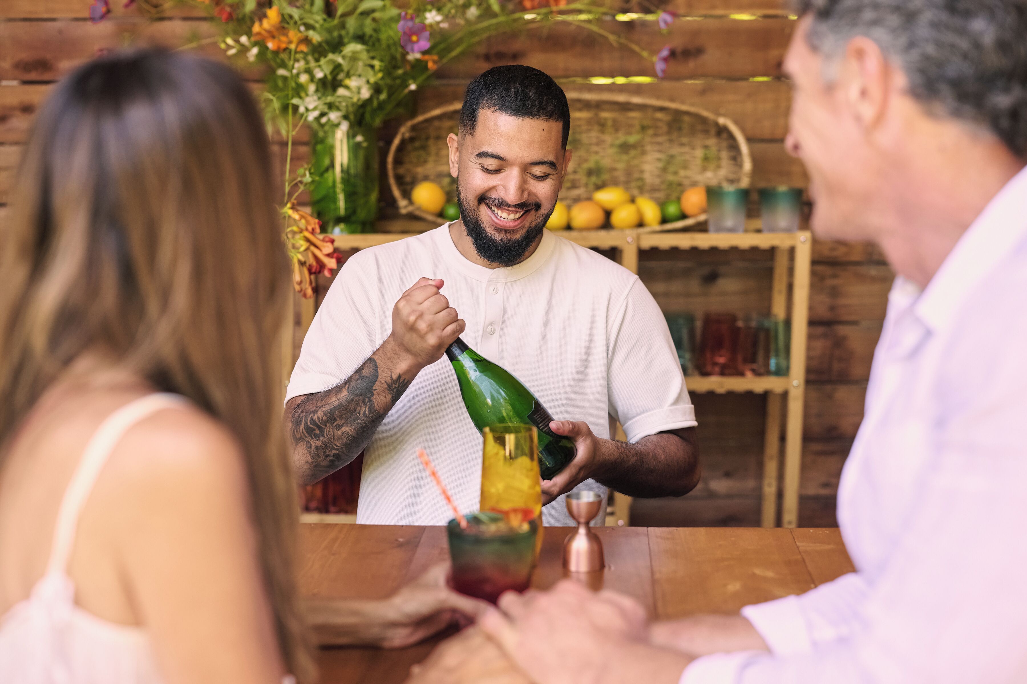 A bar setting with a bartender pouring a drink into a glass.