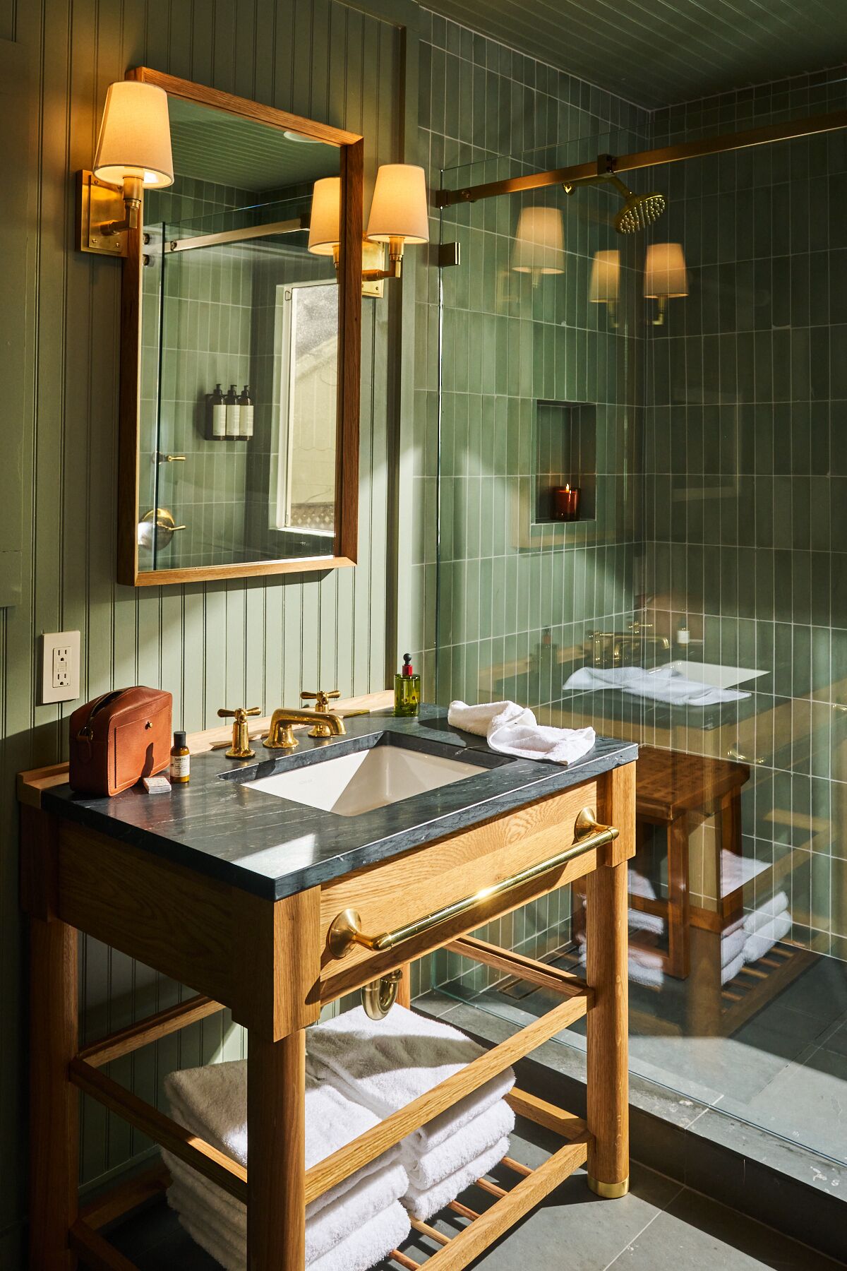Un baño con tocador de madera, un espejo grande y una cabina de ducha de vidrio.