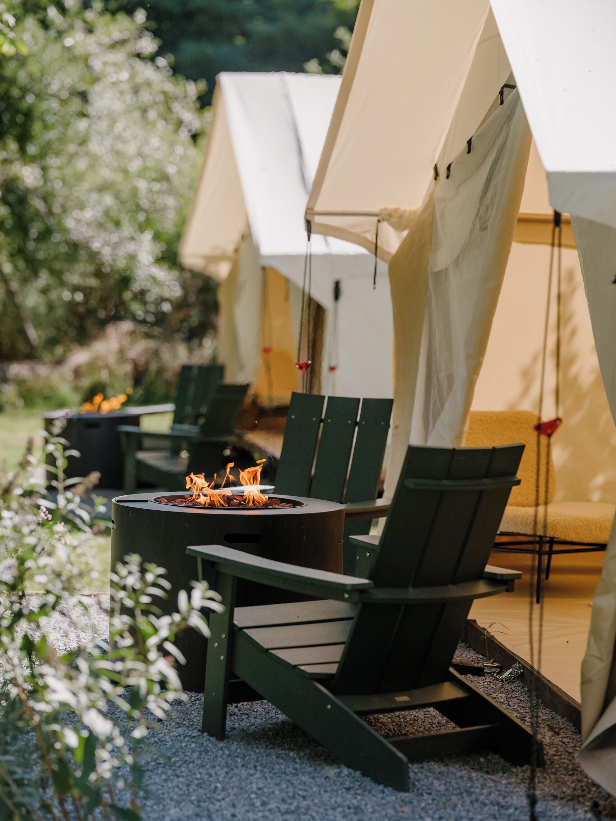 A row of tents with outdoor seating and a fire pit.