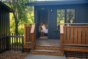 A cabin with a wooden deck, a door marked with the number 50, and a view of a bed inside.