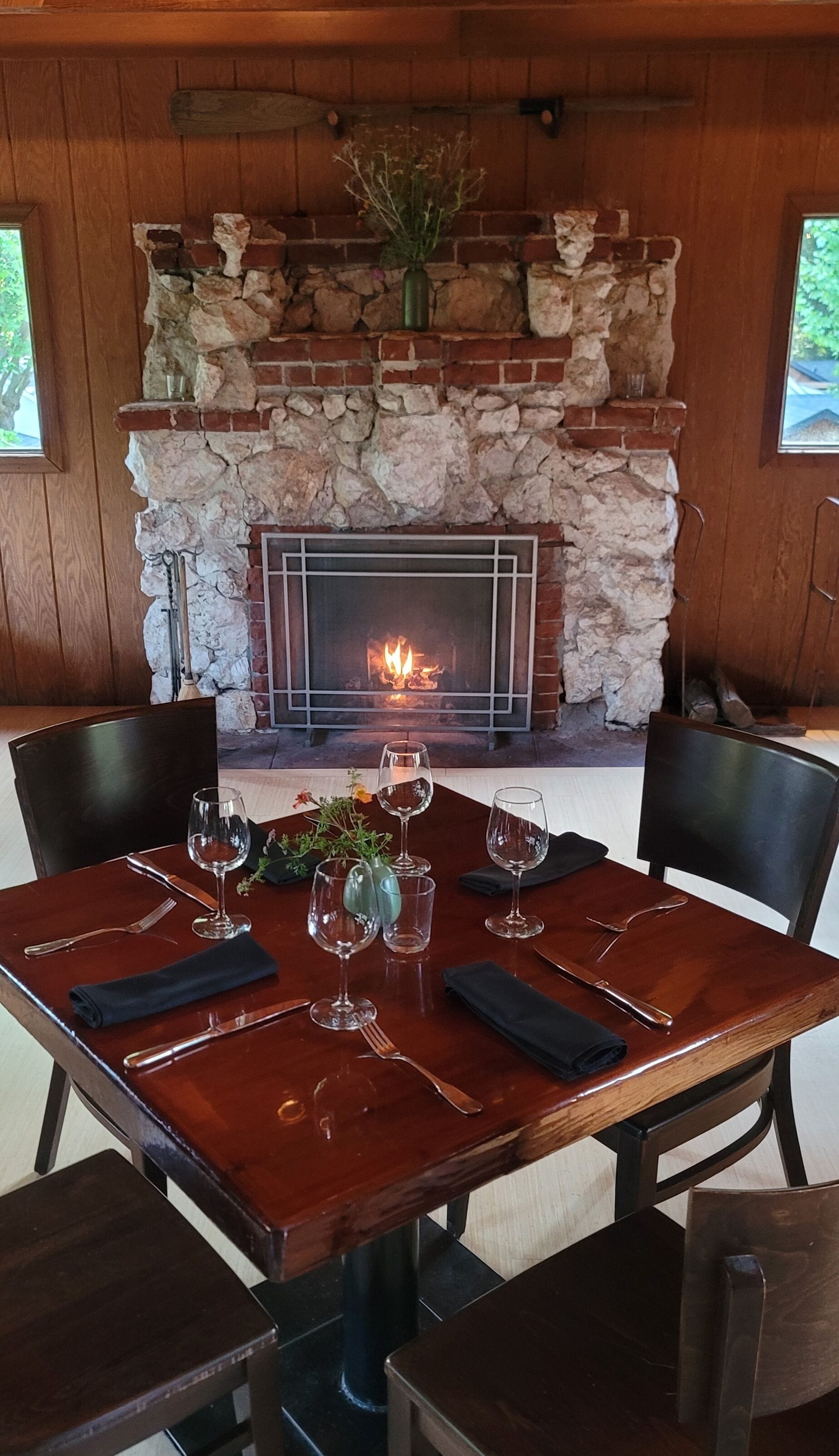 A dining table set for six with a fireplace in the background.