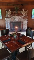 A dining table set for six with a fireplace in the background.