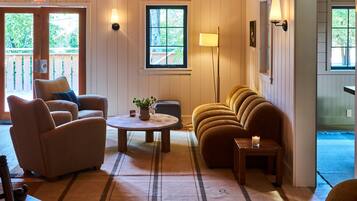 A cozy room with wooden beams, a sofa, a chair, a small table, and a lamp.