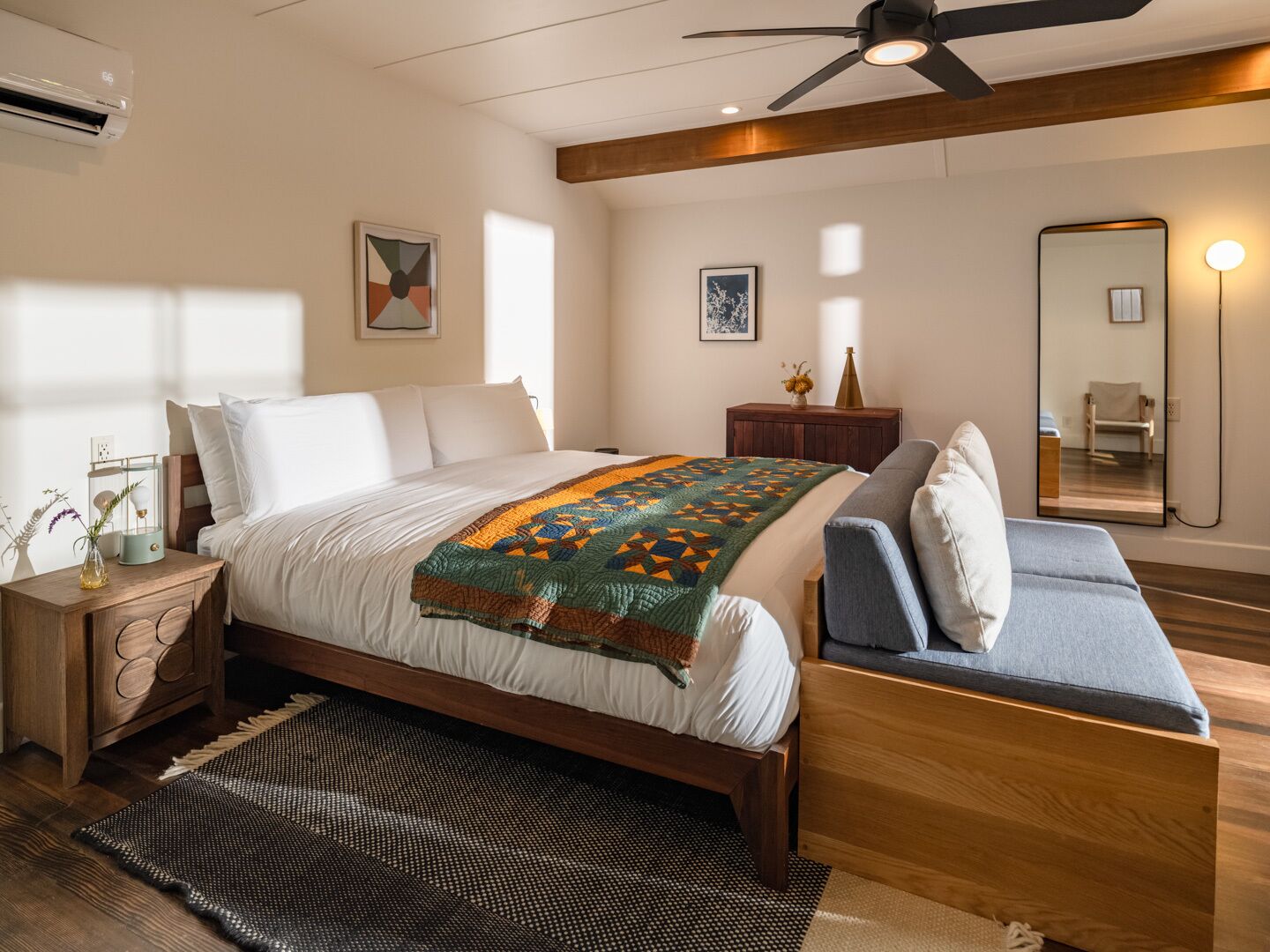 Un dormitorio moderno con cama, mesita de noche y un espejo grande.