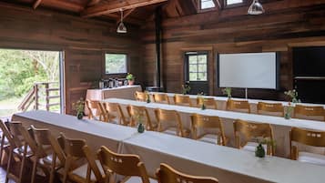 A long dining table with chairs, wooden walls, and a projector screen.