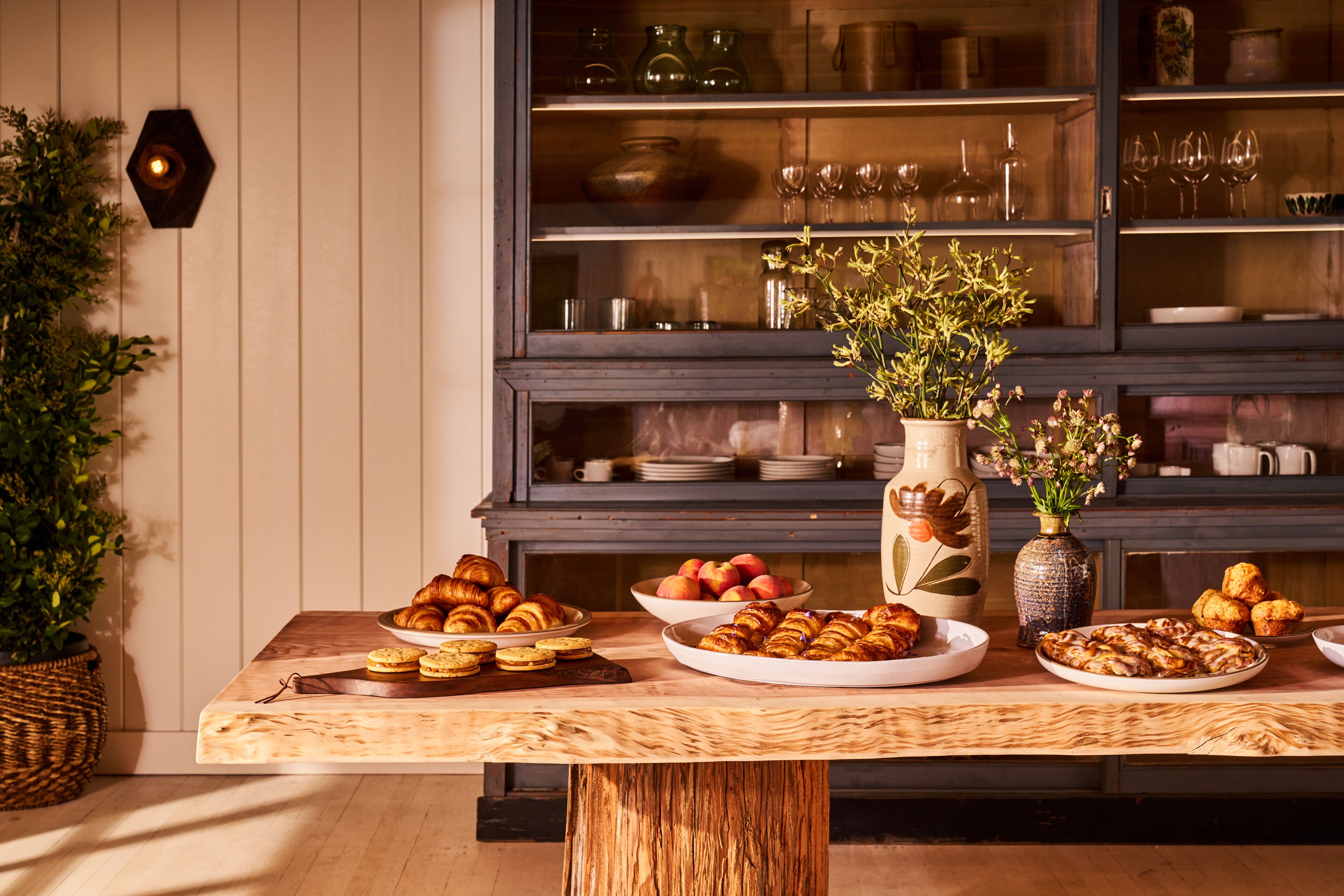 A wooden table with pastries and a vase of flowers.