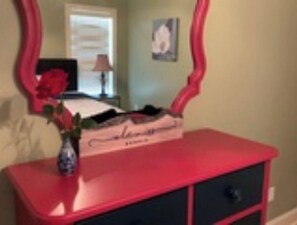 A red dresser with a mirror and a vase with flowers.