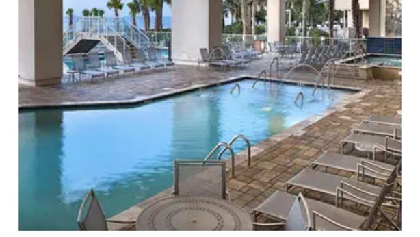 A pool area with lounge chairs and a staircase leading to a deck. - Luxury 2 Bedroom unit in beachfront Myrtle Beach resort Sleeps 8 (Myrtle Beach)