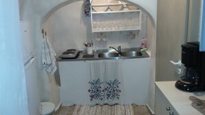 Uma cozinha compacta com pia, cafeteira e um pequeno balcão.