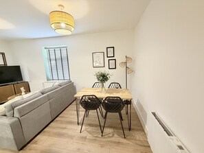 A modern living room with a sofa, dining table, chairs, a TV, and artwork on the walls. - Courtyard View (Southampton)