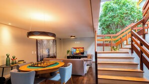 Una sala de estar moderna con una mesa de comedor de madera, sillas, un sofá, un televisor y una escalera.