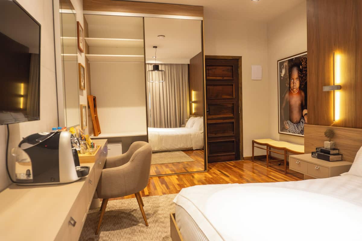 Una camera d'albergo moderna con un letto, una scrivania, una sedia e un grande specchio.