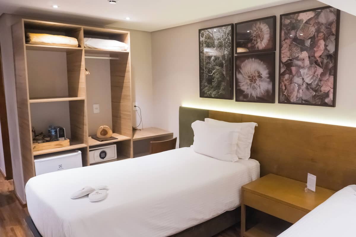 Una camera d'albergo con un letto, un comodino, un armadio e una parete decorata con opere d'arte.