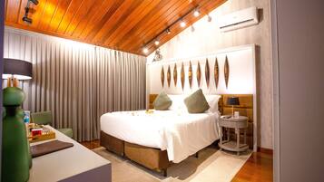 A hotel room with a wooden ceiling, a bed with white bedding, a bedside table with a lamp, and a wall-mounted air conditioner.